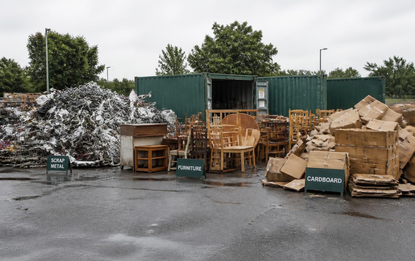 Separated piles of scrap metal, furniture and cardboard at a sorting yard